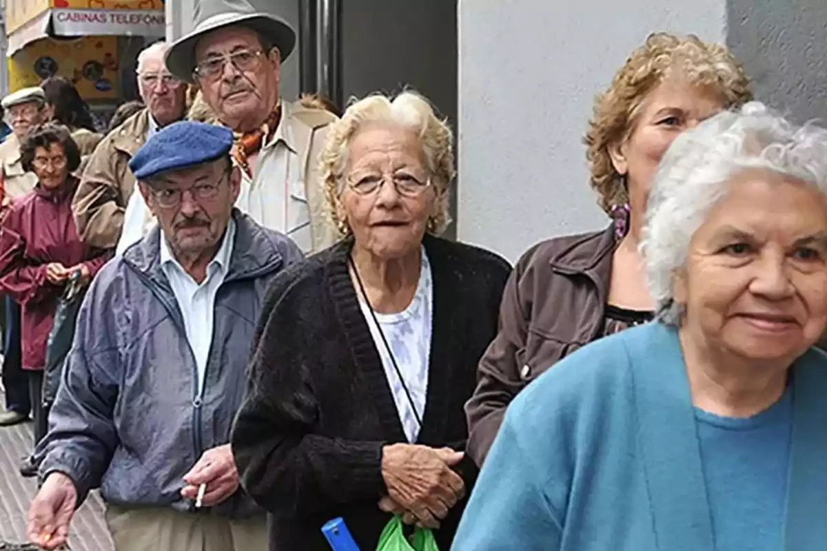 Un grupo de personas mayores haciendo fila en la calle.