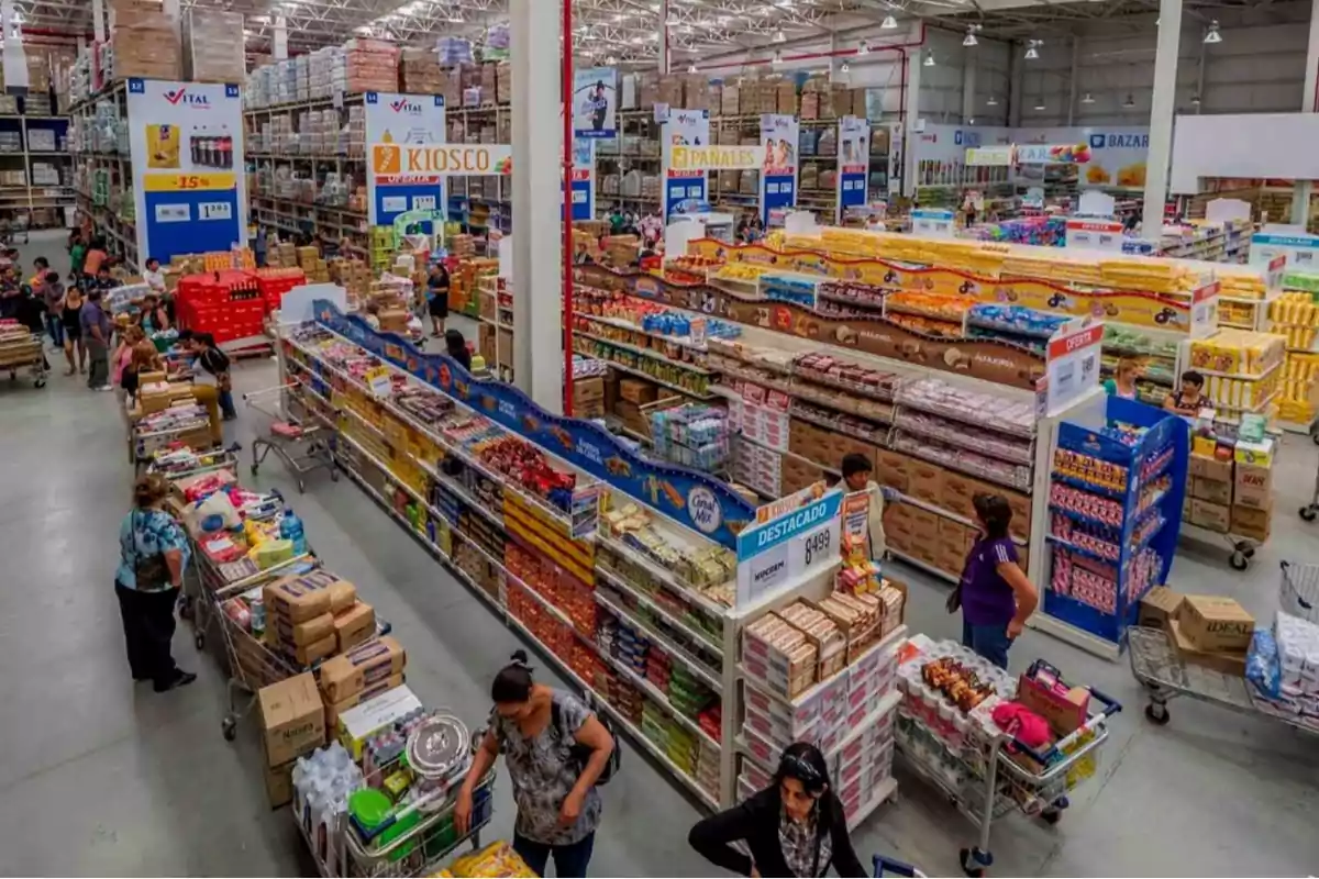 Vista aérea de un supermercado con pasillos llenos de productos y personas comprando.