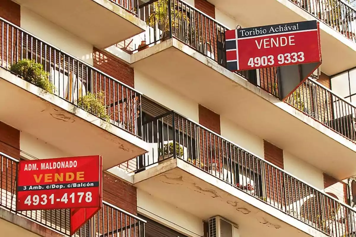 Edificio de departamentos con carteles de venta en los balcones.