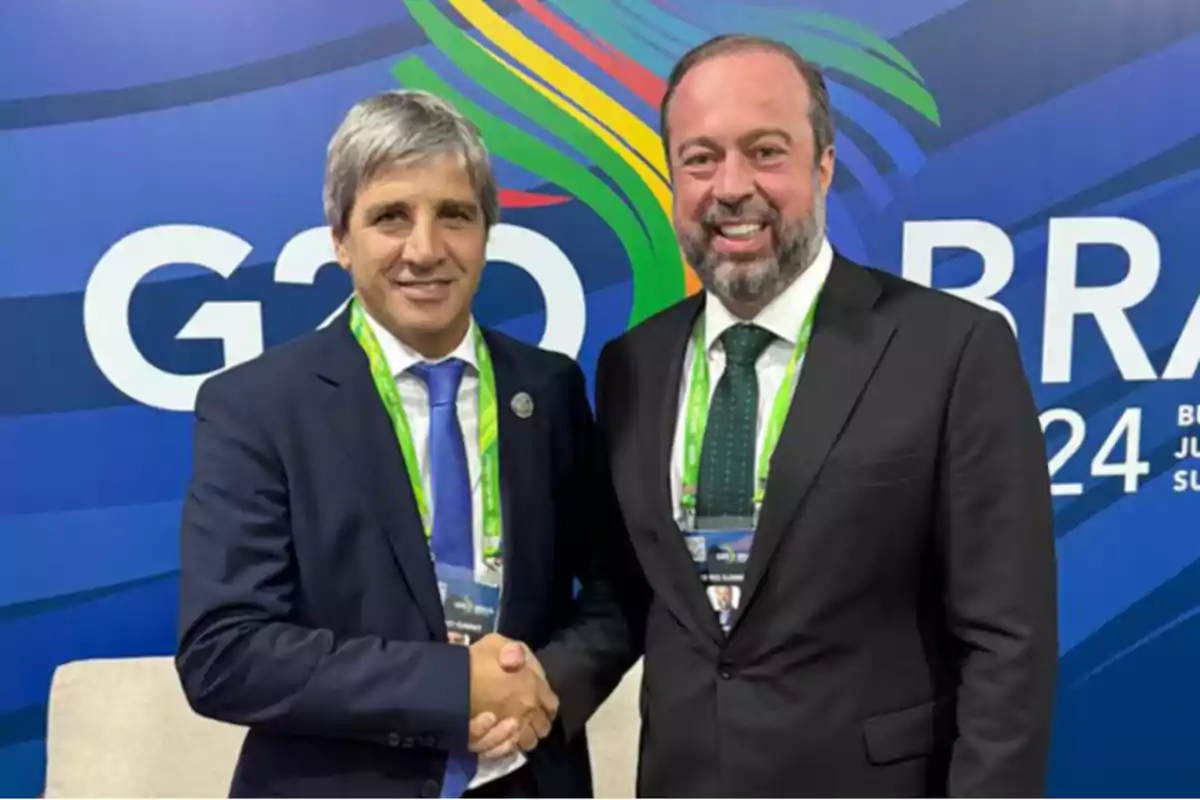 Dos hombres de traje se dan la mano frente a un fondo con el logo del G20 en Brasil.