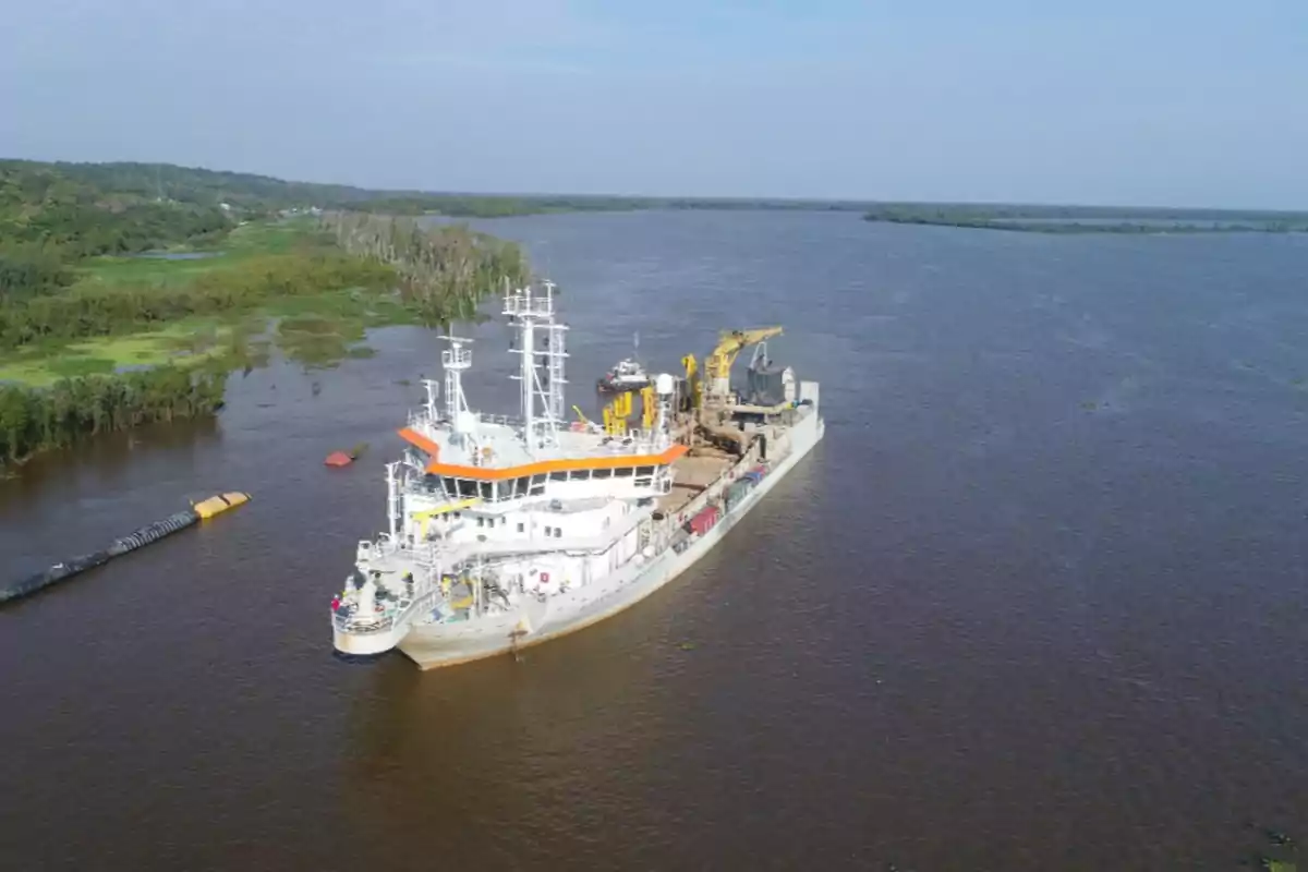 Un barco grande navegando por un río rodeado de vegetación.