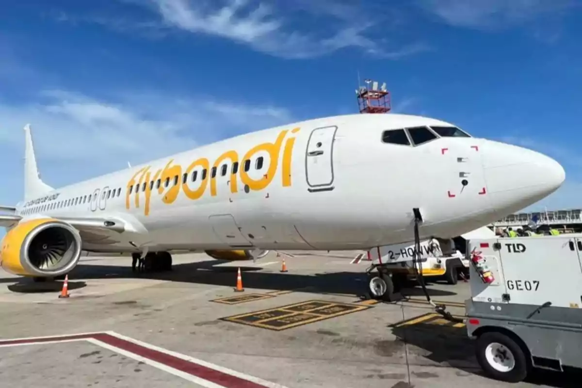 Un avión de la aerolínea Flybondi estacionado en la pista de un aeropuerto bajo un cielo despejado.