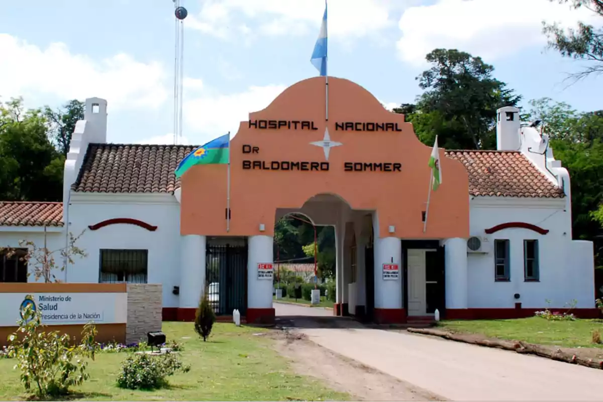 Entrada principal del Hospital Nacional Dr. Baldomero Sommer con banderas ondeando y un cartel del Ministerio de Salud.