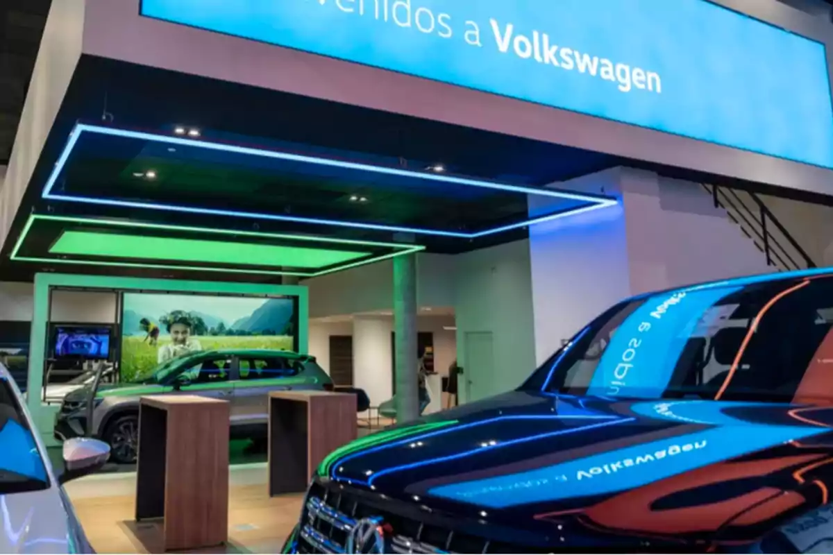 Exhibición de autos Volkswagen en un concesionario moderno con iluminación azul y verde.