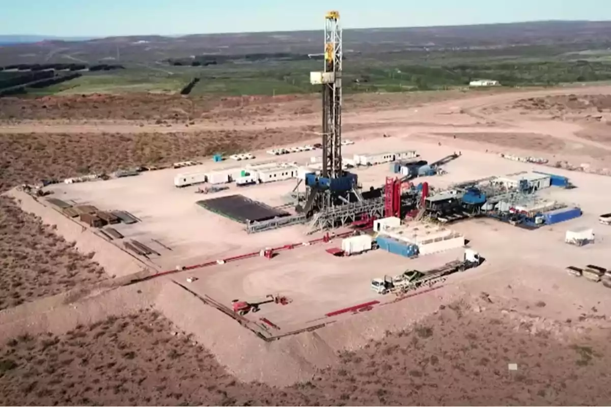 Vista aérea de una plataforma de perforación en un área desértica con equipos y vehículos alrededor.