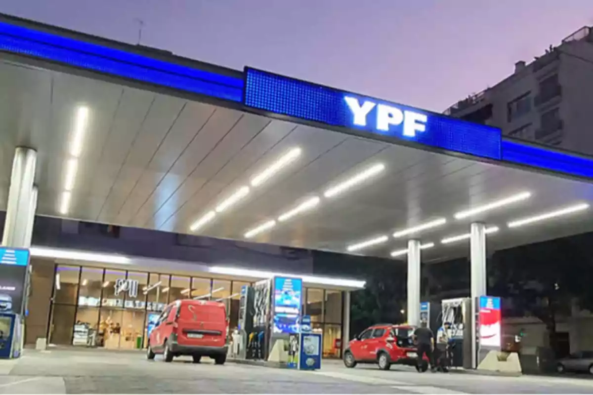 Estación de servicio YPF iluminada al anochecer con vehículos en el área de carga.