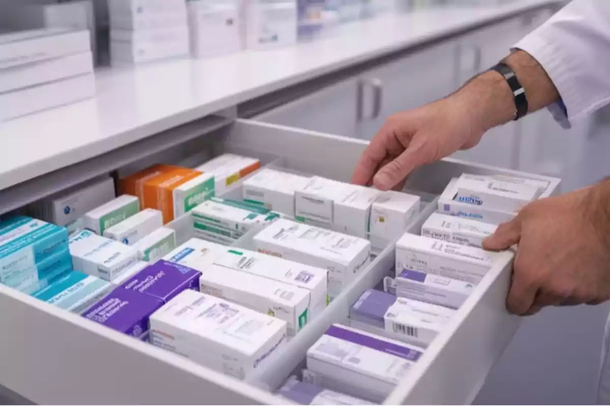 Una persona organizando cajas de medicamentos en un cajón de farmacia.