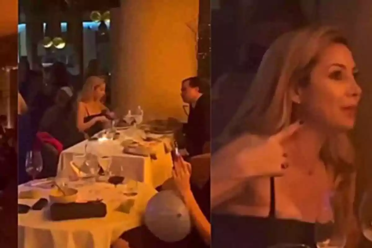 Una mujer rubia está sentada en un restaurante elegante con mesas decoradas con manteles blancos y copas de vino, mientras conversa con un hombre frente a ella.