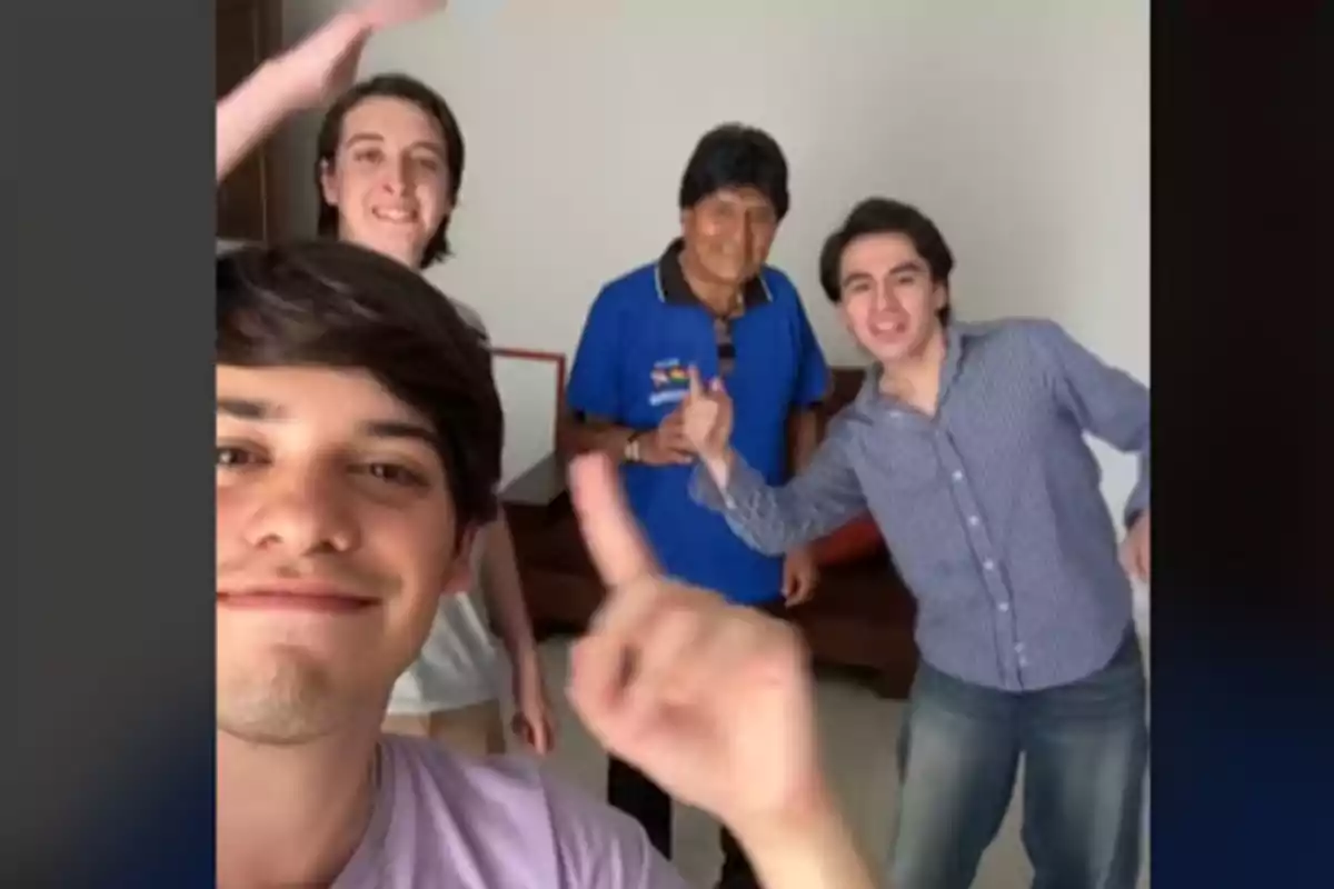 Un grupo de cuatro personas sonríe y posa para una selfie en una habitación.