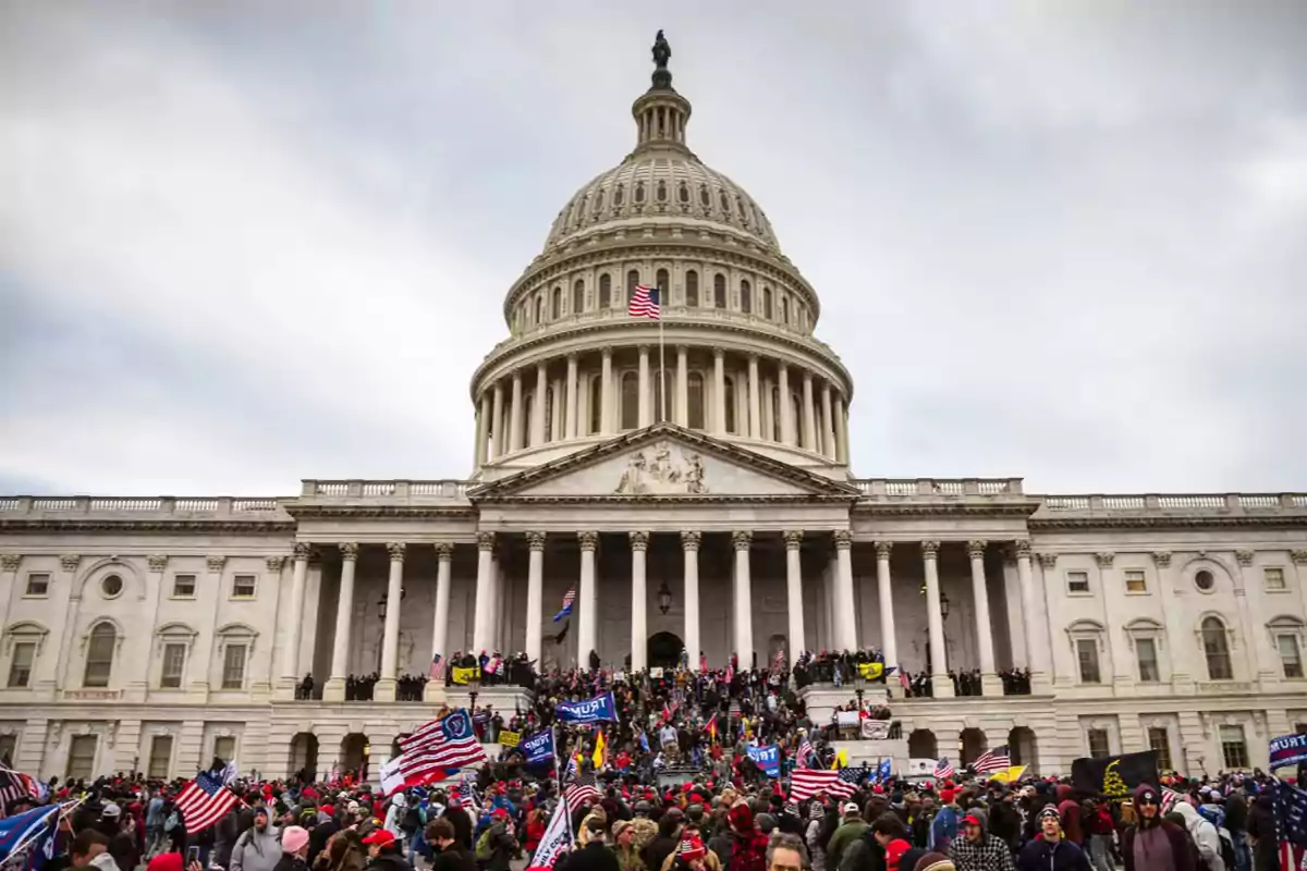 Multitud reunida frente al edificio del Capitolio de los Estados Unidos con banderas y pancartas.