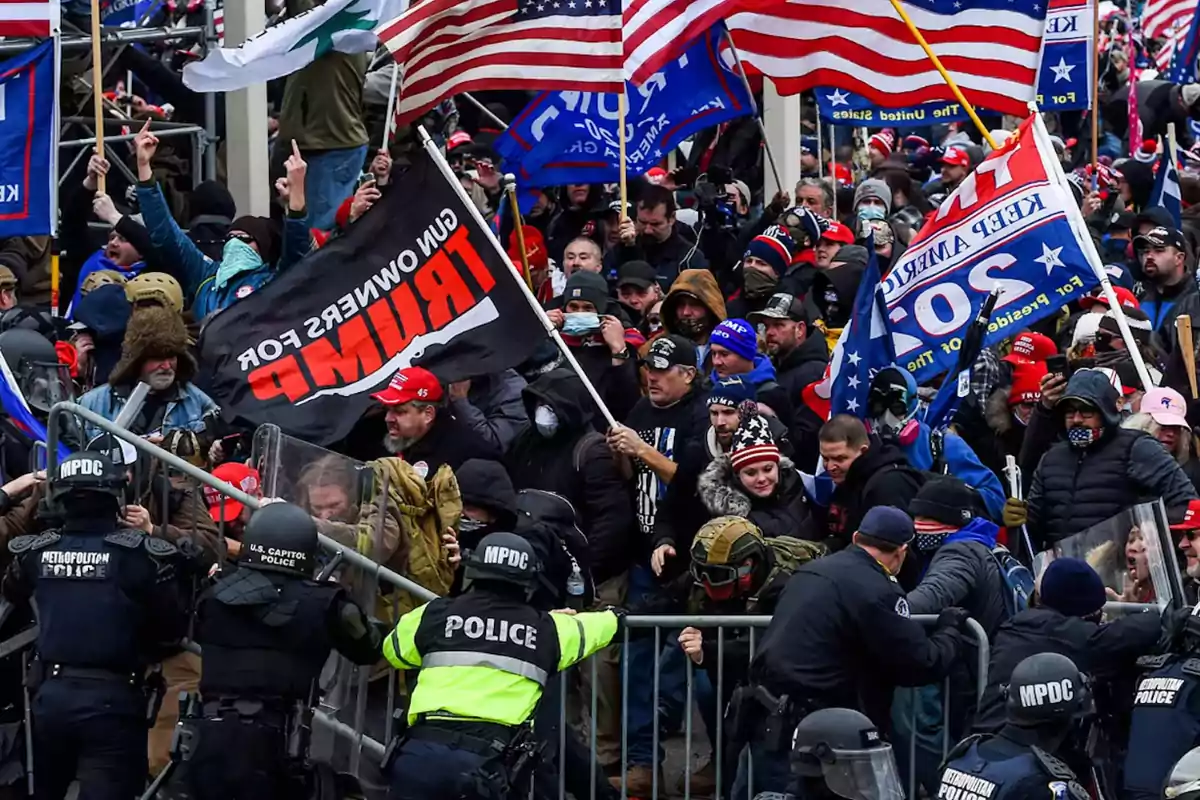 Una multitud de personas con banderas y carteles se enfrenta a la policía en una protesta.