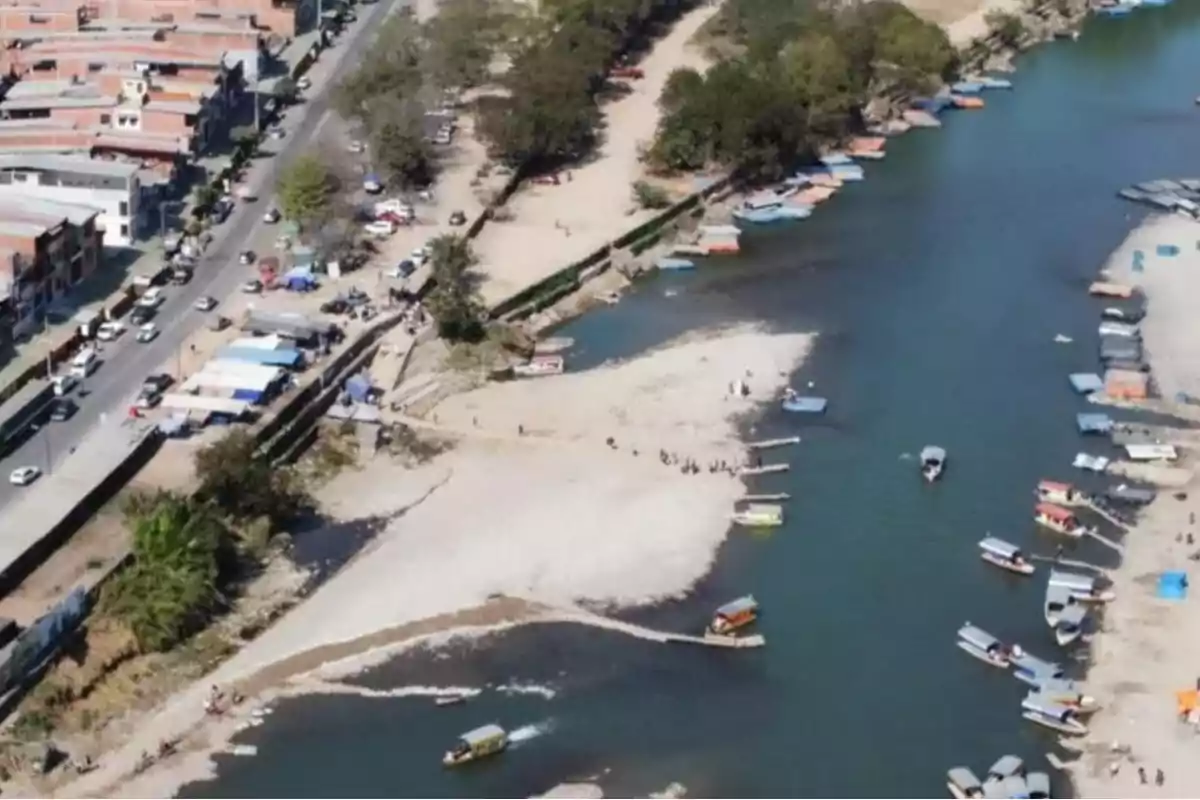 Vista aérea de un río con embarcaciones pequeñas y una zona urbana cercana.