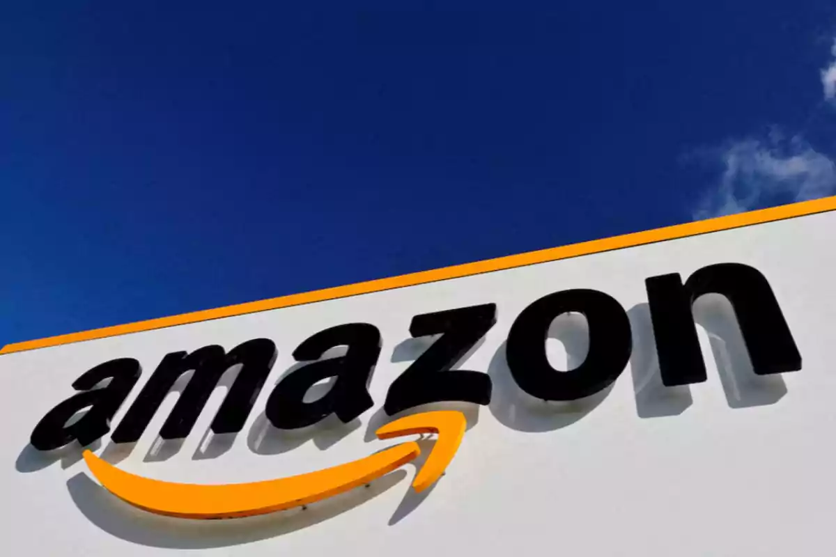 Logo de Amazon en un edificio con cielo azul de fondo.