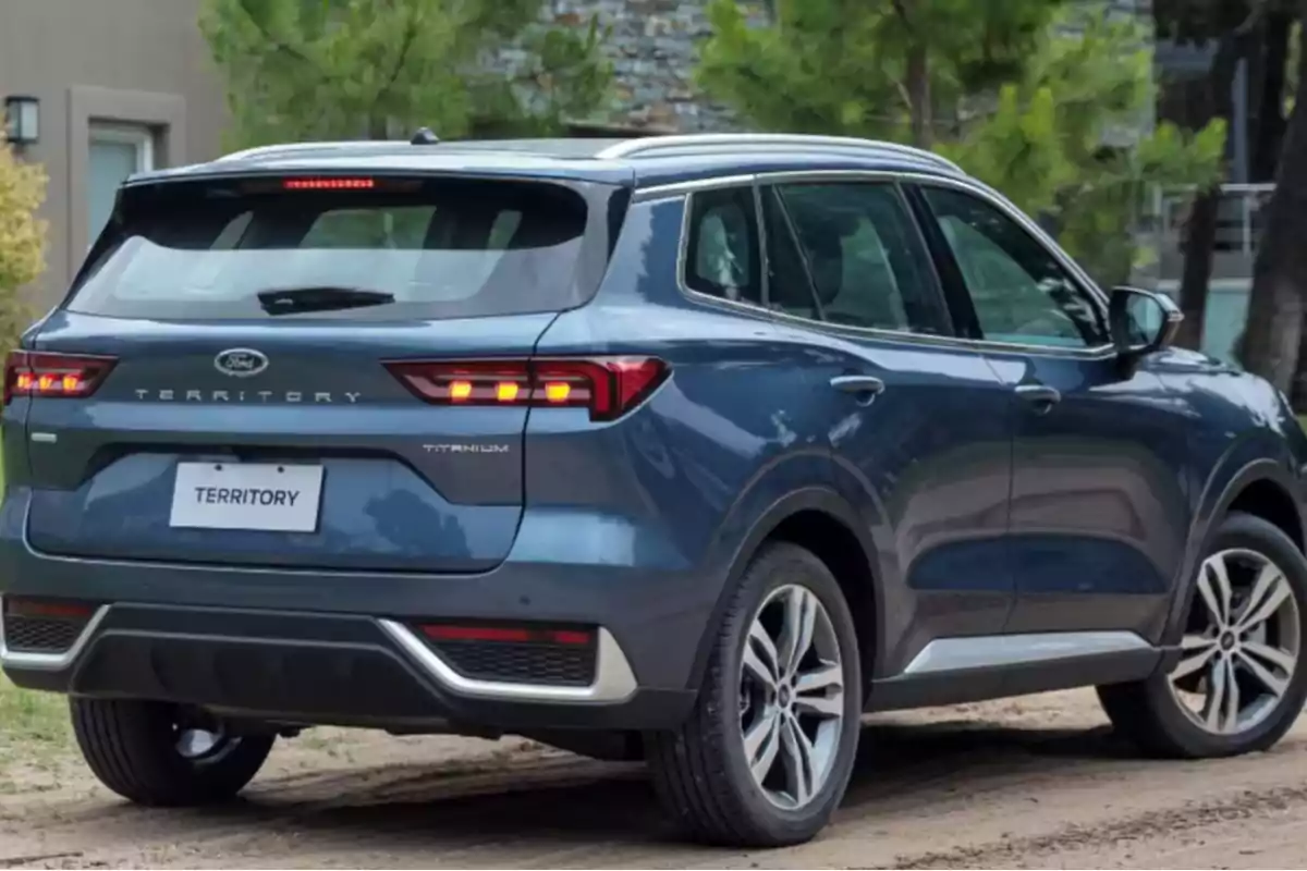 SUV azul estacionada en un camino de tierra con árboles al fondo.