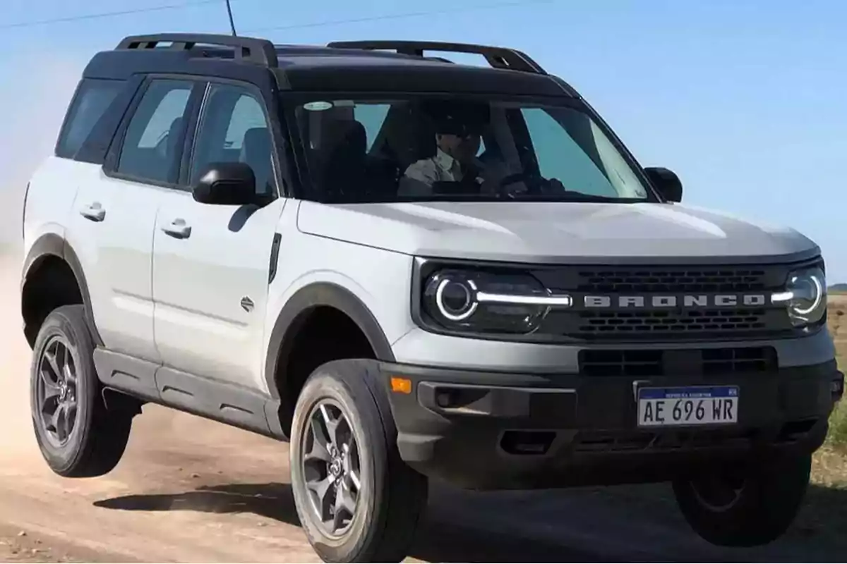 Un SUV blanco en movimiento sobre un camino de tierra.