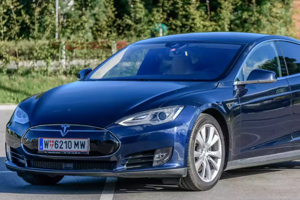 Un coche eléctrico azul estacionado en un aparcamiento al aire libre.