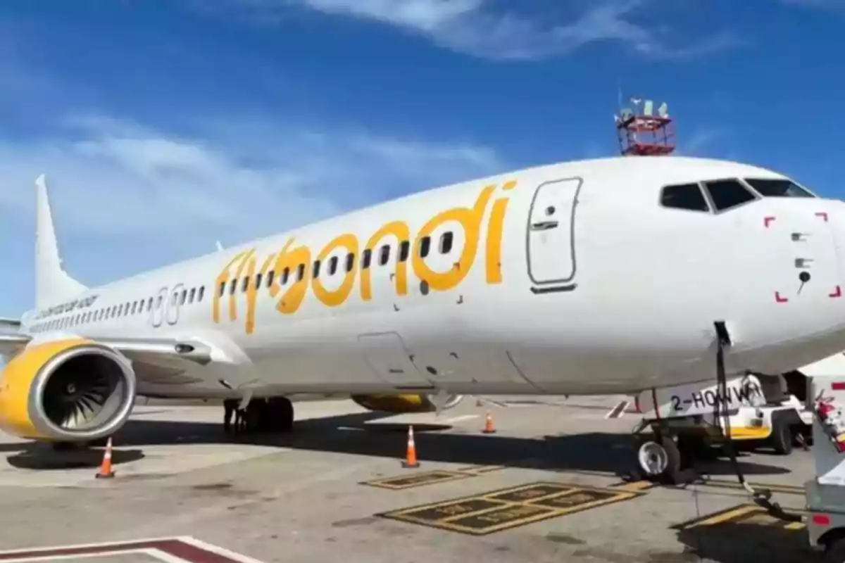 Un avión de la aerolínea Flybondi estacionado en el aeropuerto con un cielo azul de fondo.