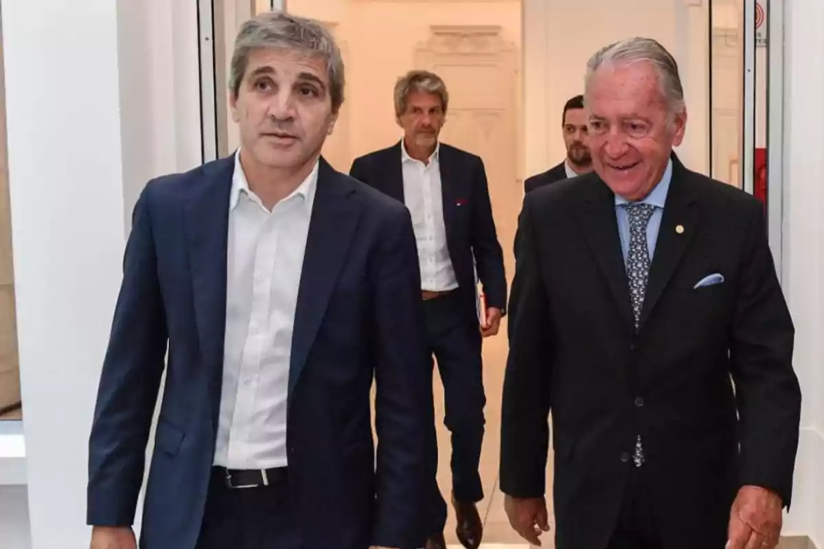 Un grupo de hombres vestidos con trajes formales camina por un pasillo iluminado.