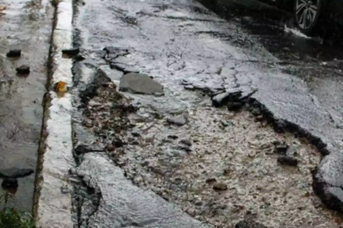 Damaged road with potholes and puddles of water after the rain.