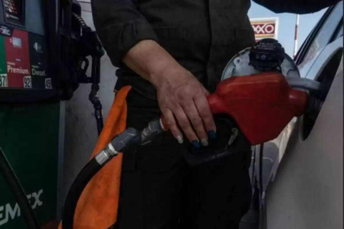 Person filling a car's tank with gasoline at a gas station.