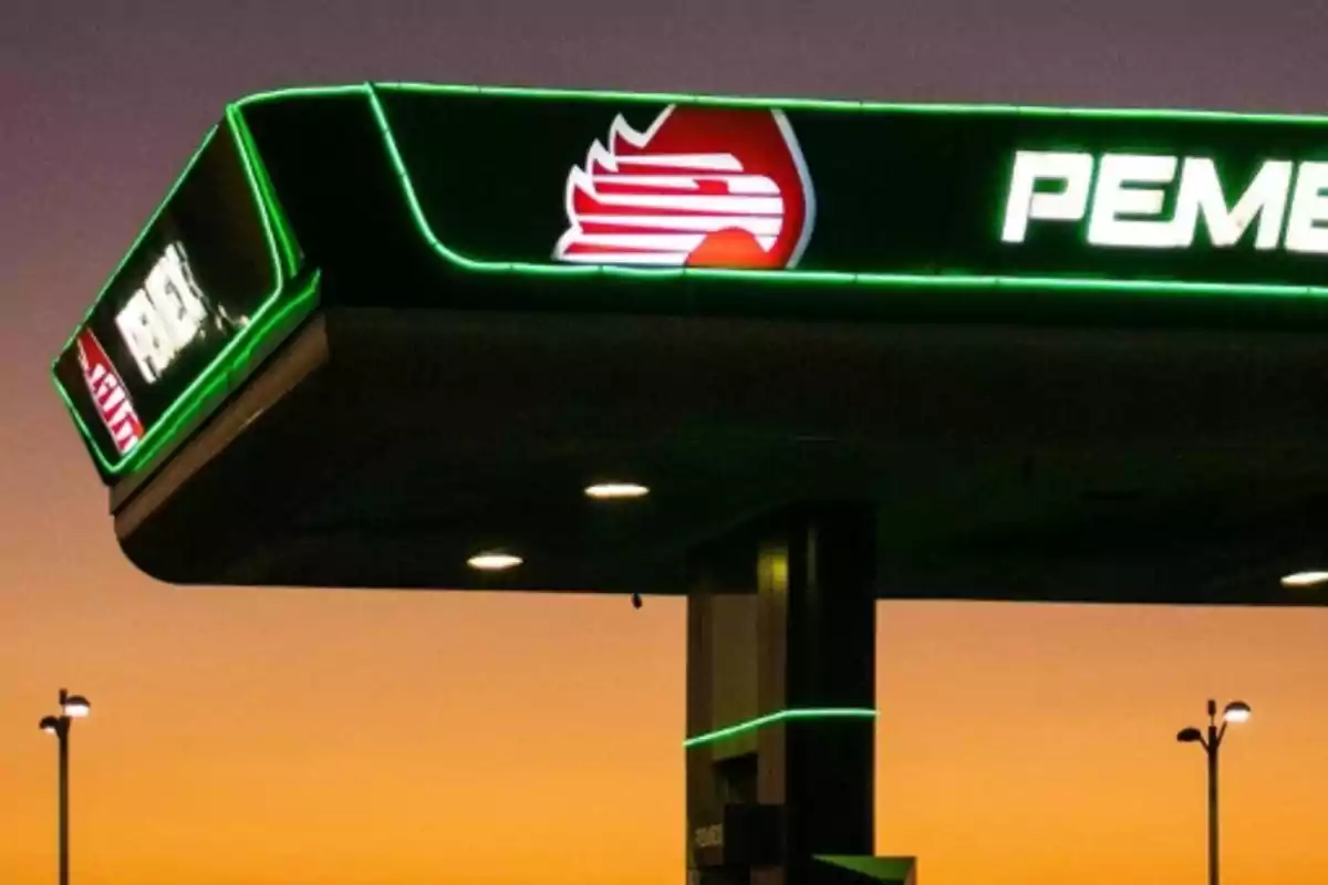 Gas station roof with illuminated logo at sunset.