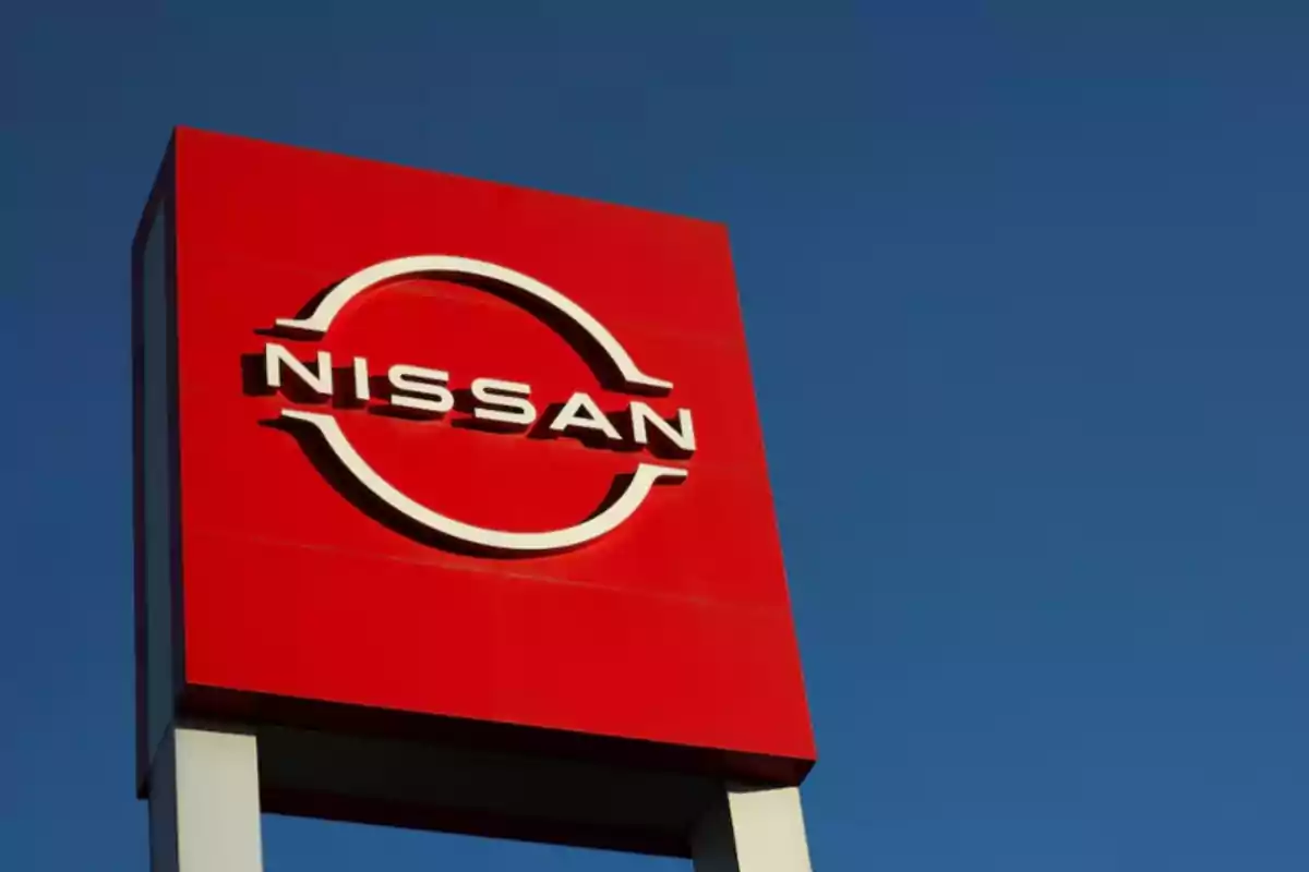 A red Nissan sign with the logo in white against a blue sky background.