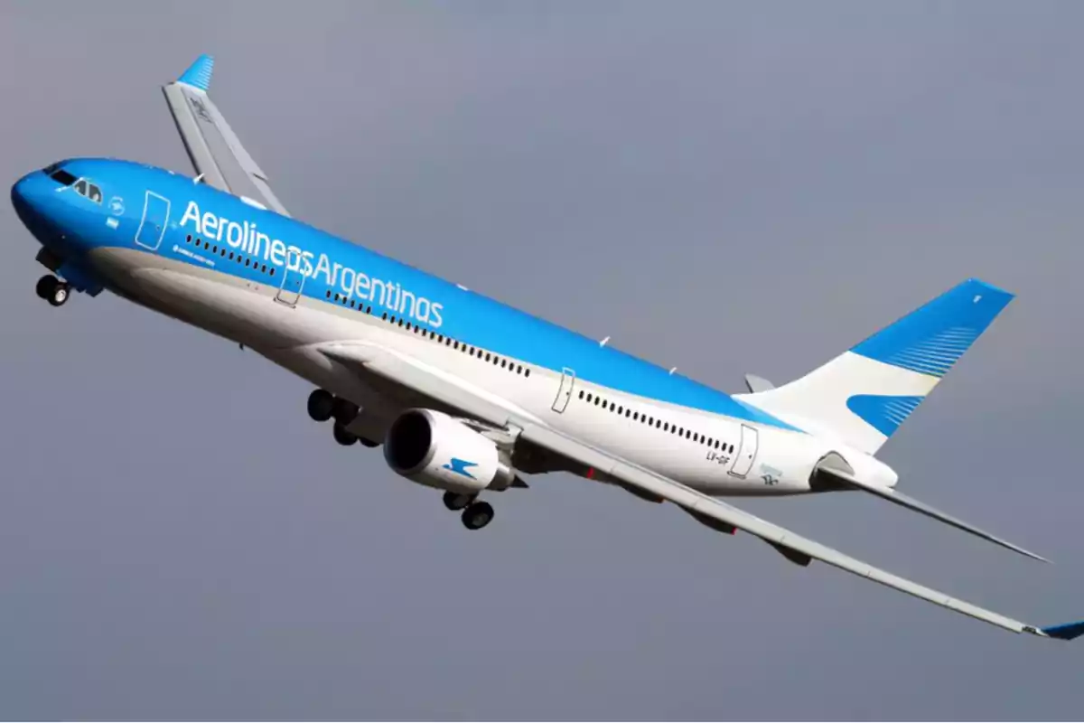 An Aerolíneas Argentinas plane in mid-flight with the sky in the background.