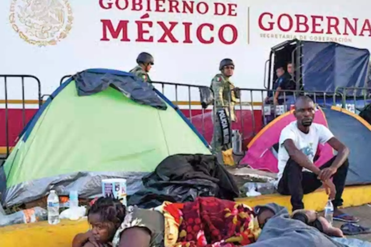 Personas descansando junto a tiendas de campaña frente a un edificio del gobierno de México, con oficiales de policía en el fondo.