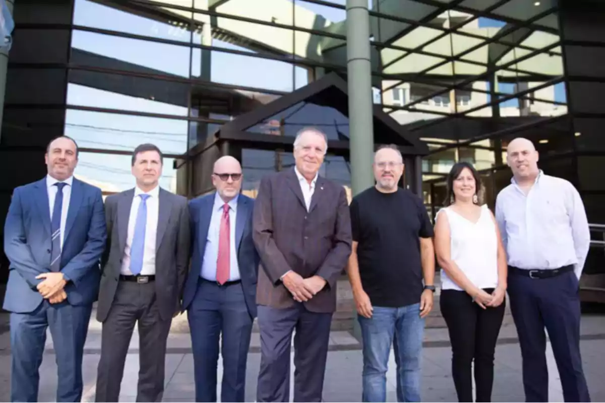 Un grupo de personas posando frente a un edificio con fachada de vidrio.