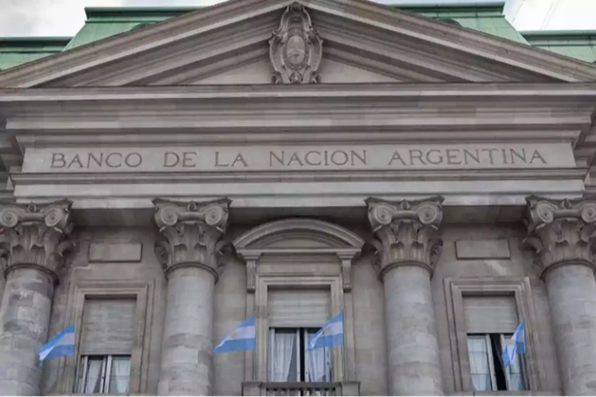 Fachada del edificio del Banco de la Nación Argentina con columnas y banderas argentinas.