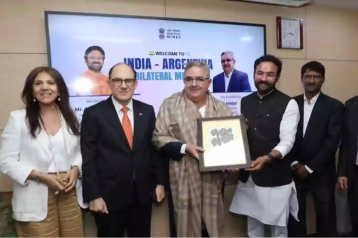 Un grupo de personas posando para una foto en un evento de reunión bilateral entre India y Argentina, con un cartel de bienvenida en el fondo.