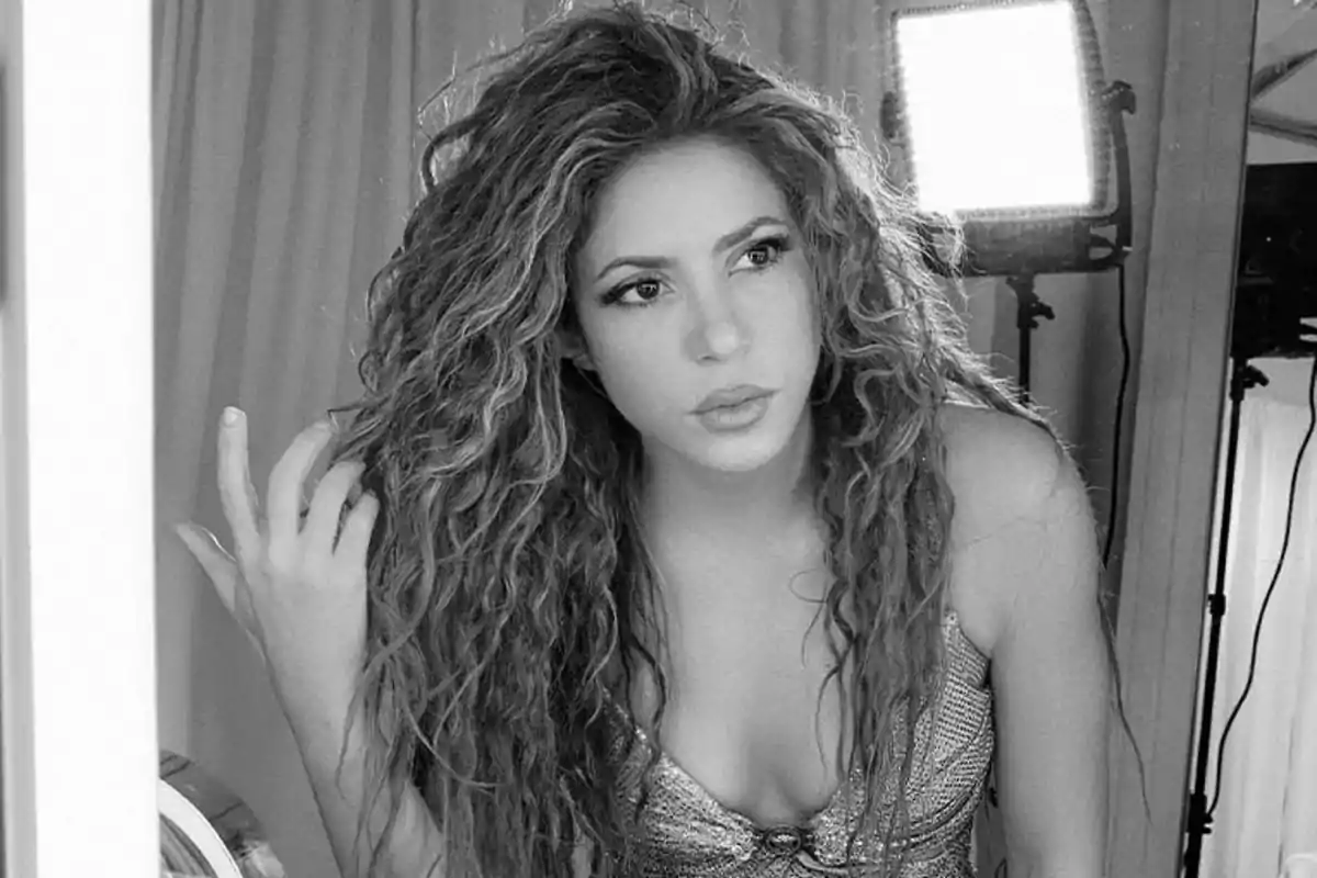 A person with curly hair posing in front of a mirror in a photography studio setting.