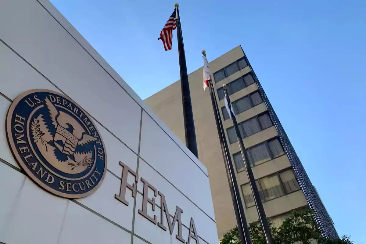 Edificio de FEMA con el logotipo del Departamento de Seguridad Nacional de EE. UU. y banderas ondeando frente a un cielo despejado.