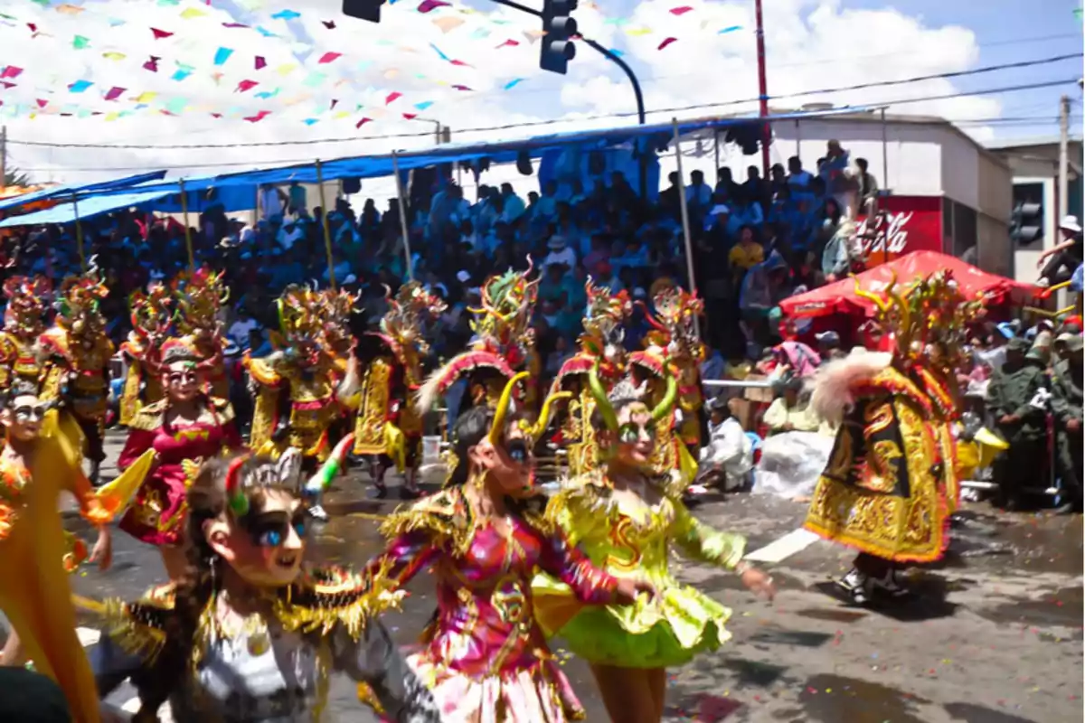 A group of people dressed in colorful costumes and elaborate masks participates in an outdoor festive parade while the audience watches from the stands.