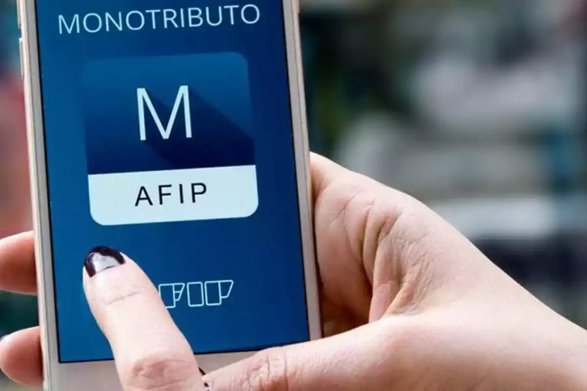 Persona sosteniendo un teléfono móvil que muestra la aplicación de monotributo de AFIP.