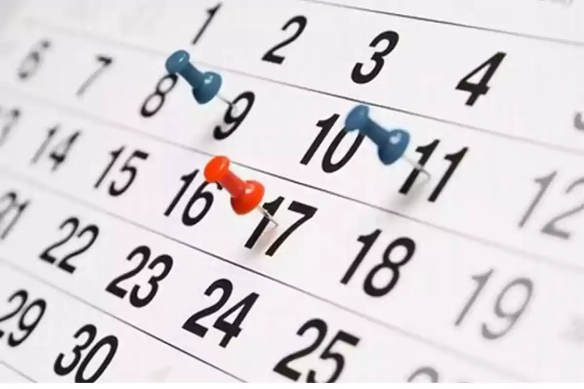 Un calendario con chinchetas de colores marcando fechas específicas.