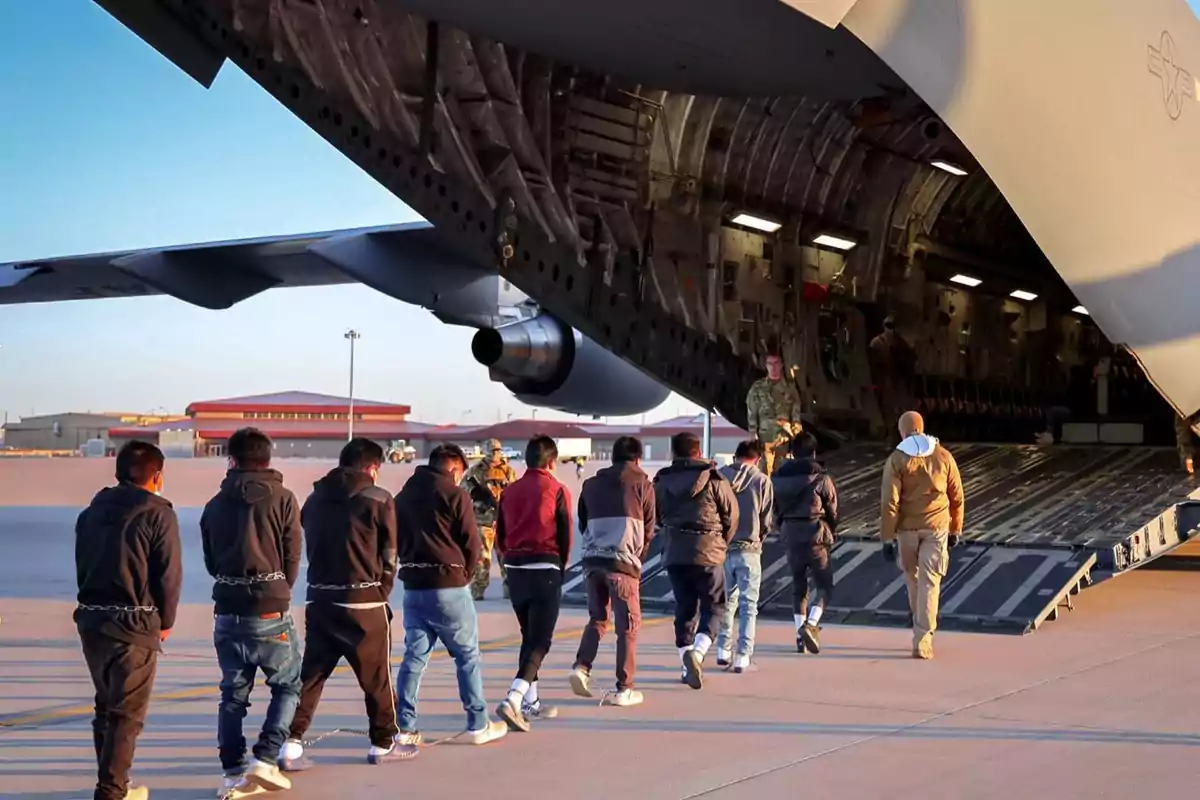 Un grupo de personas sube a un avión militar en una pista de aterrizaje.