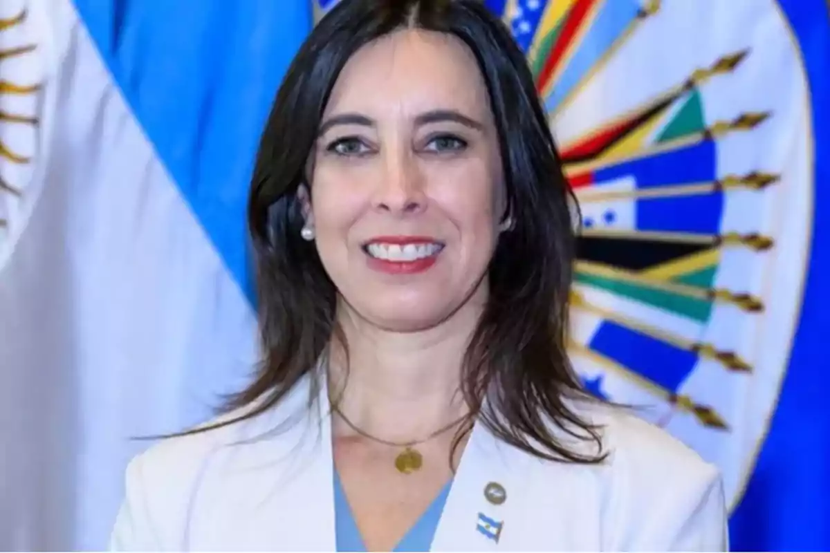 Una persona sonriendo con banderas de fondo.