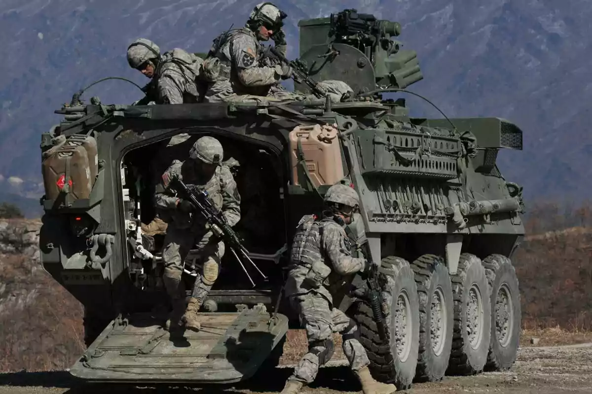 Soldados en uniforme militar descendiendo de un vehículo blindado en un entorno montañoso.