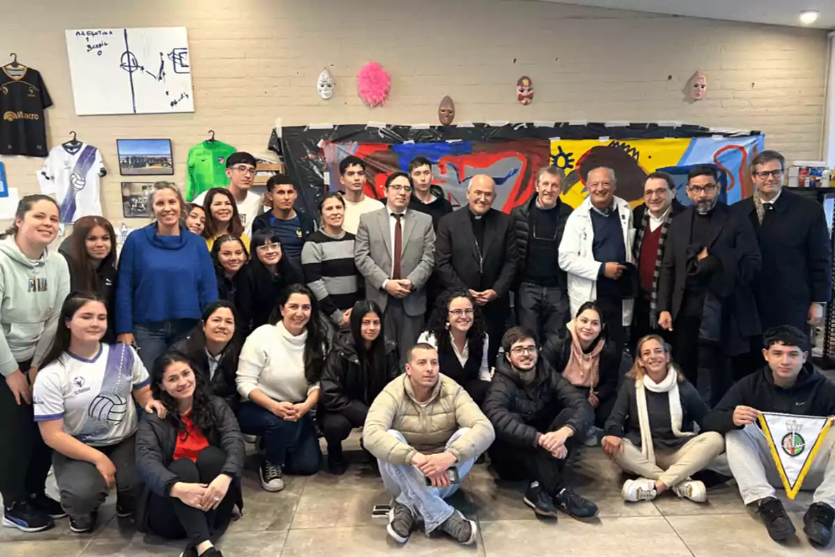 Un grupo de personas posando para una foto en un ambiente interior decorado con camisetas deportivas, cuadros y máscaras en la pared.