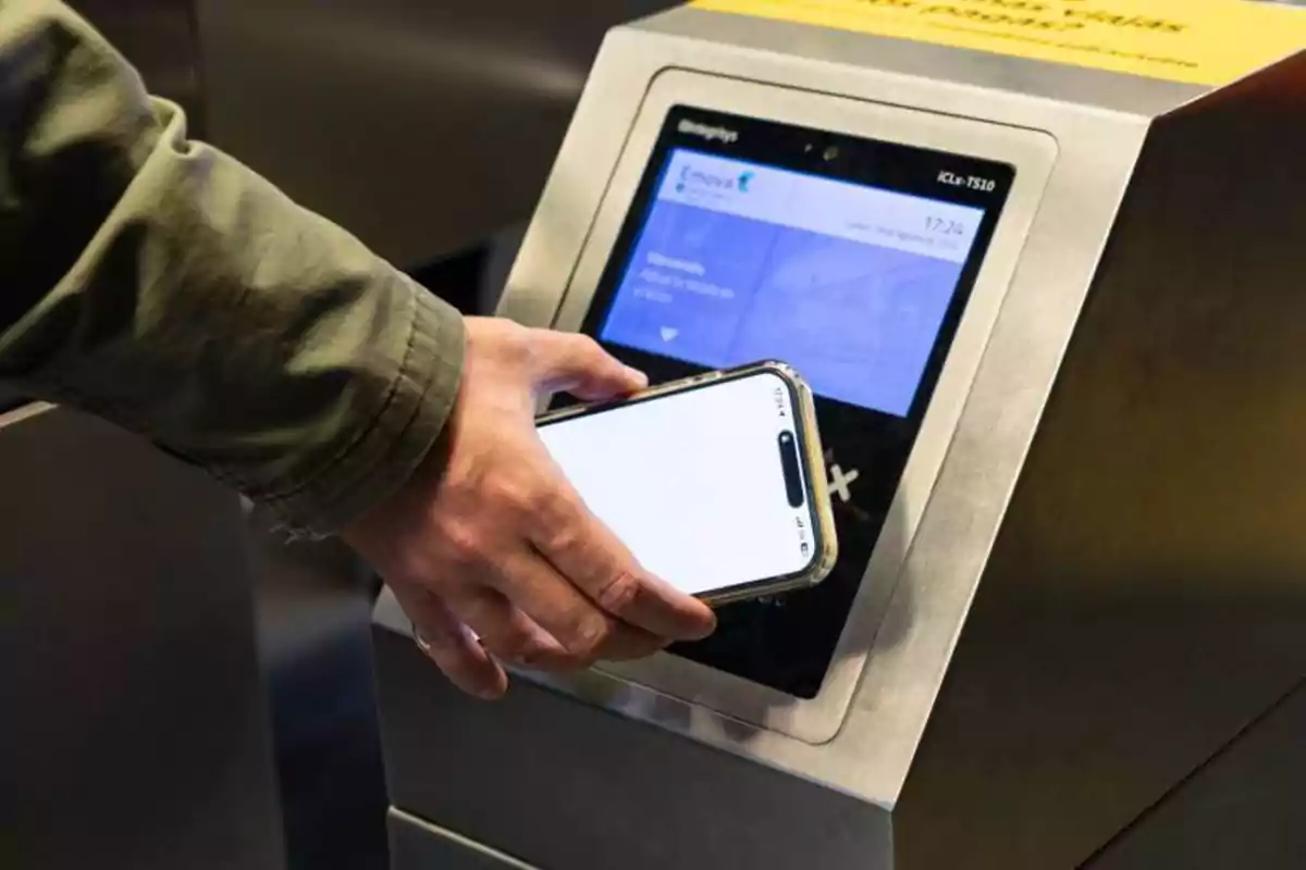 Persona usando un teléfono móvil para escanear un código en un lector de boletos electrónico.