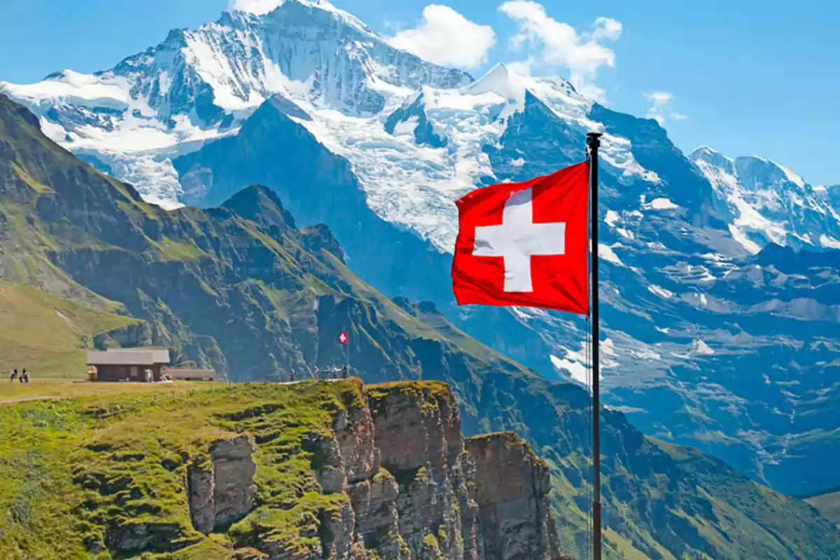 Paisaje montañoso con una bandera de Suiza ondeando en primer plano.