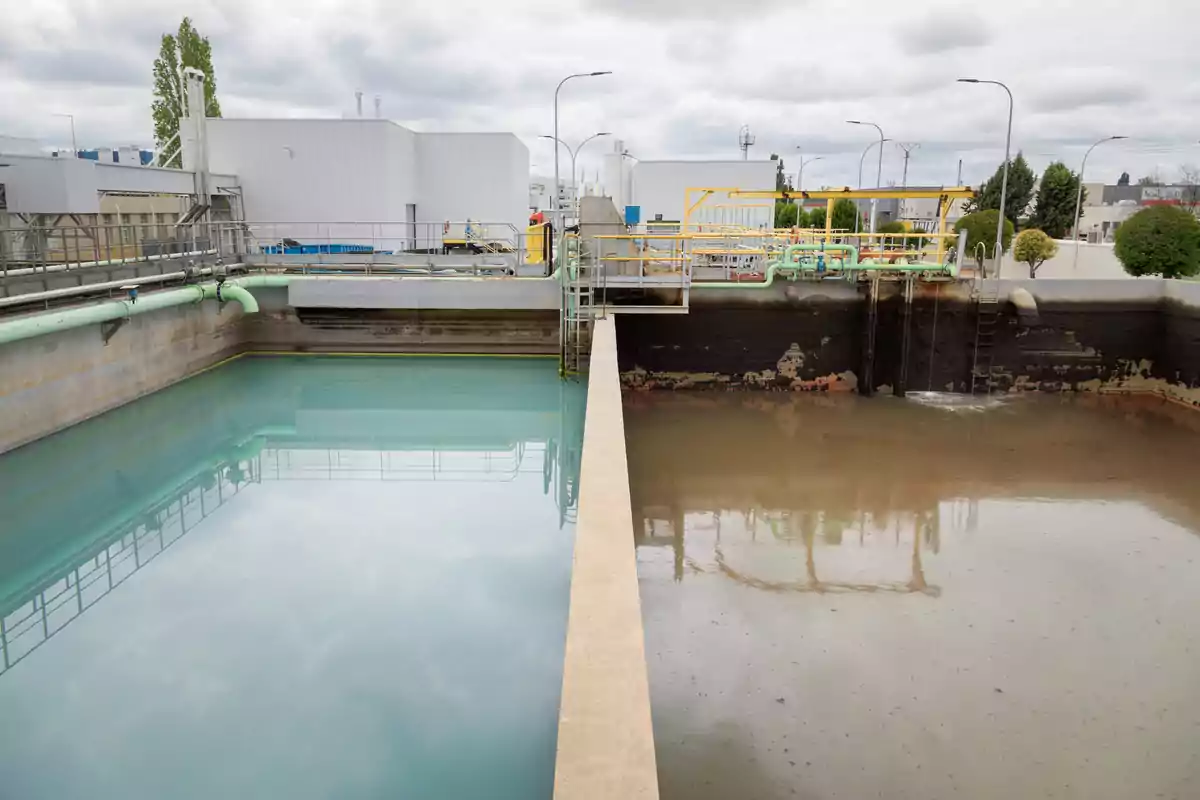 Planta de tratamiento de aguas con dos tanques, uno con agua clara y otro con agua turbia, separados por una pared de concreto.