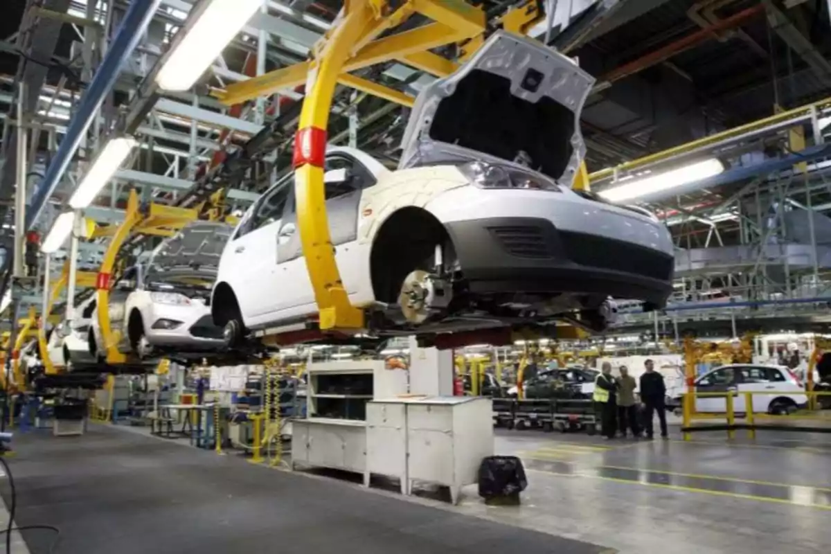 Automobile assembly line in a factory with vehicles in the process of being assembled.