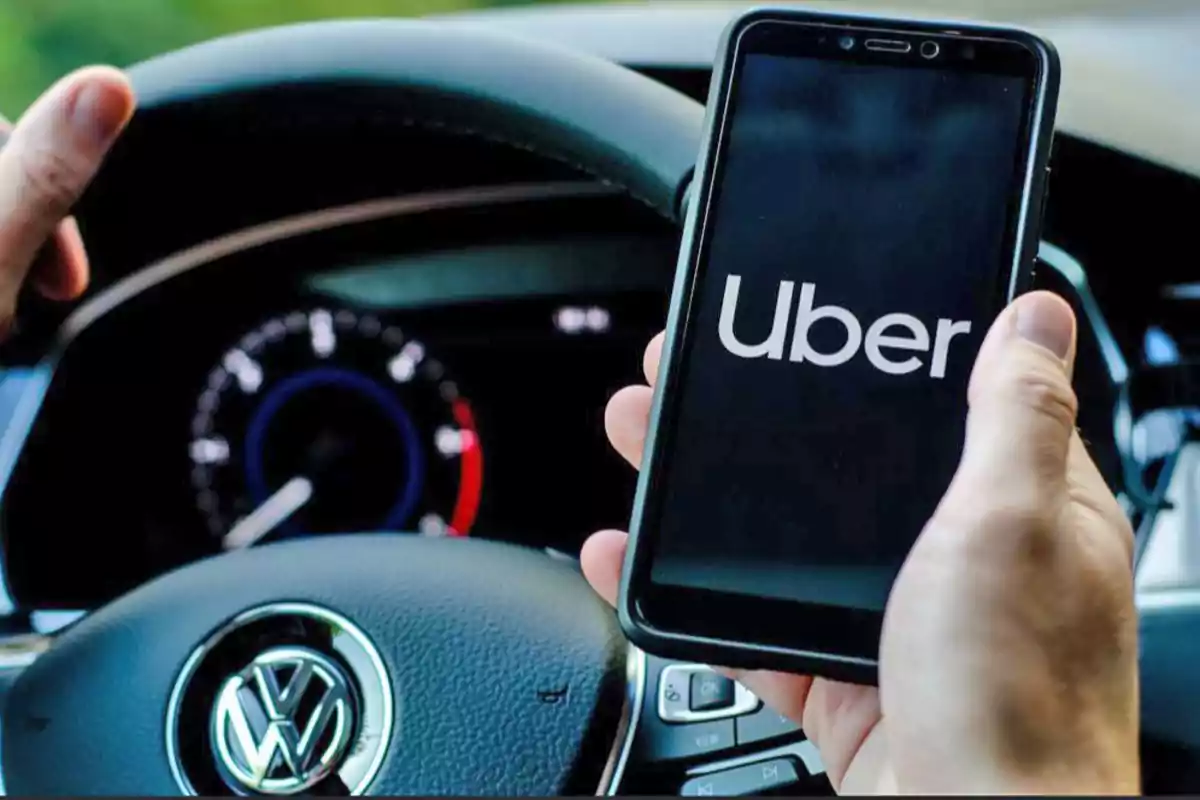 Persona sosteniendo un teléfono con la aplicación de Uber abierta mientras conduce un automóvil Volkswagen.