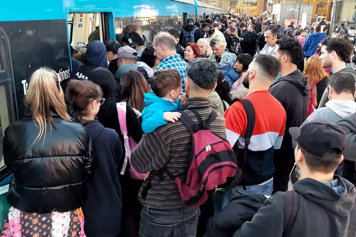 Una multitud de personas esperando para abordar un tren en una estación concurrida.