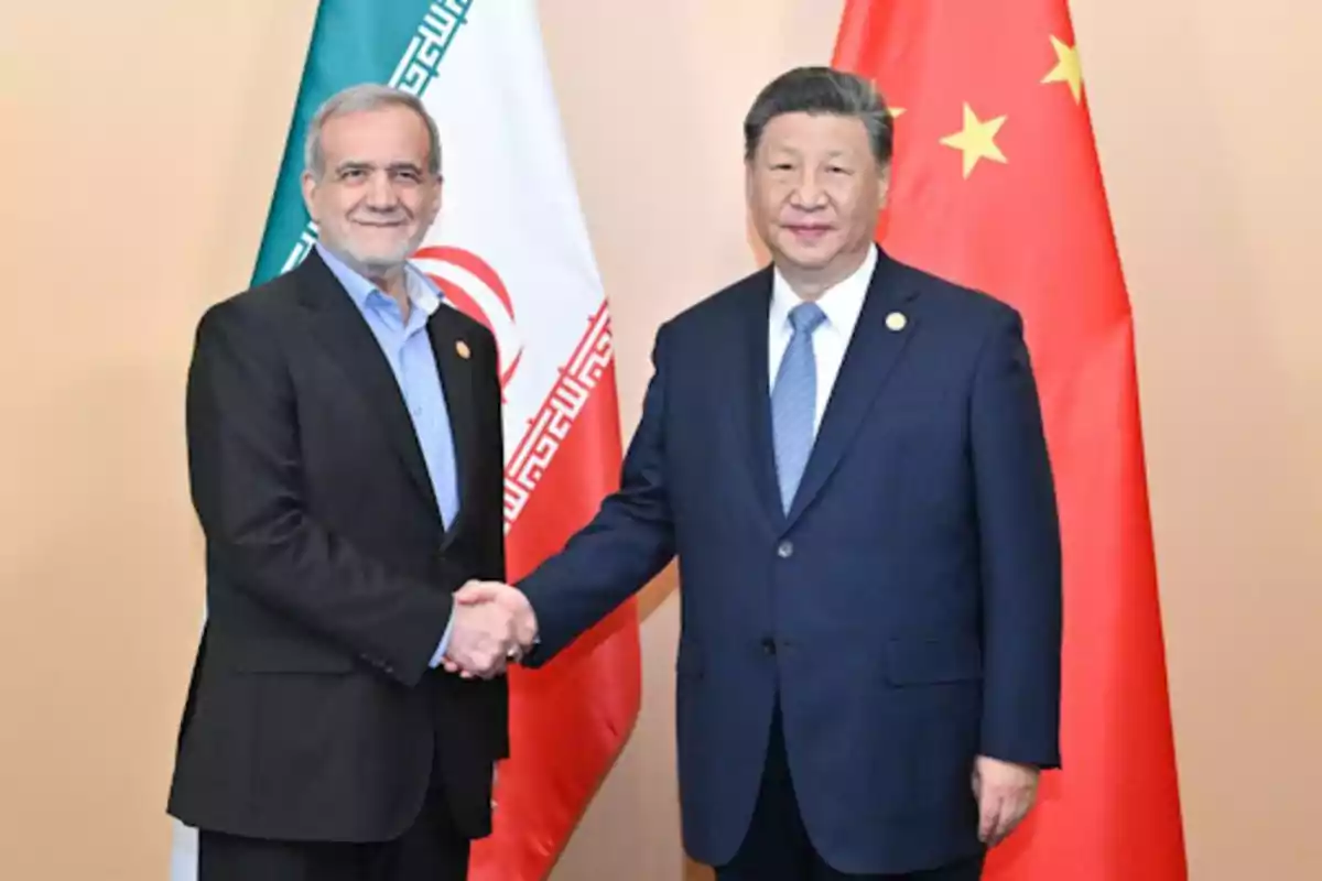 Dos hombres de traje se dan la mano frente a las banderas de Irán y China.