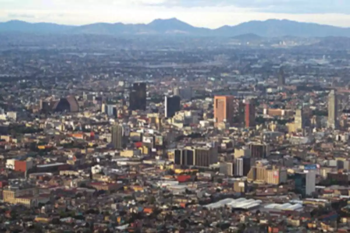 Panoramic view of a city with tall buildings and mountains in the background.