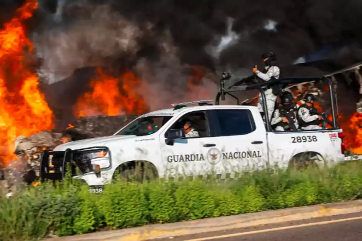 National Guard vehicle in front of a fire with intense flames in the background.