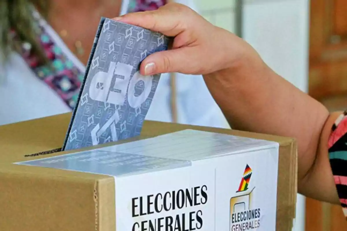 Una persona introduciendo un sobre en una urna de votación durante unas elecciones generales.